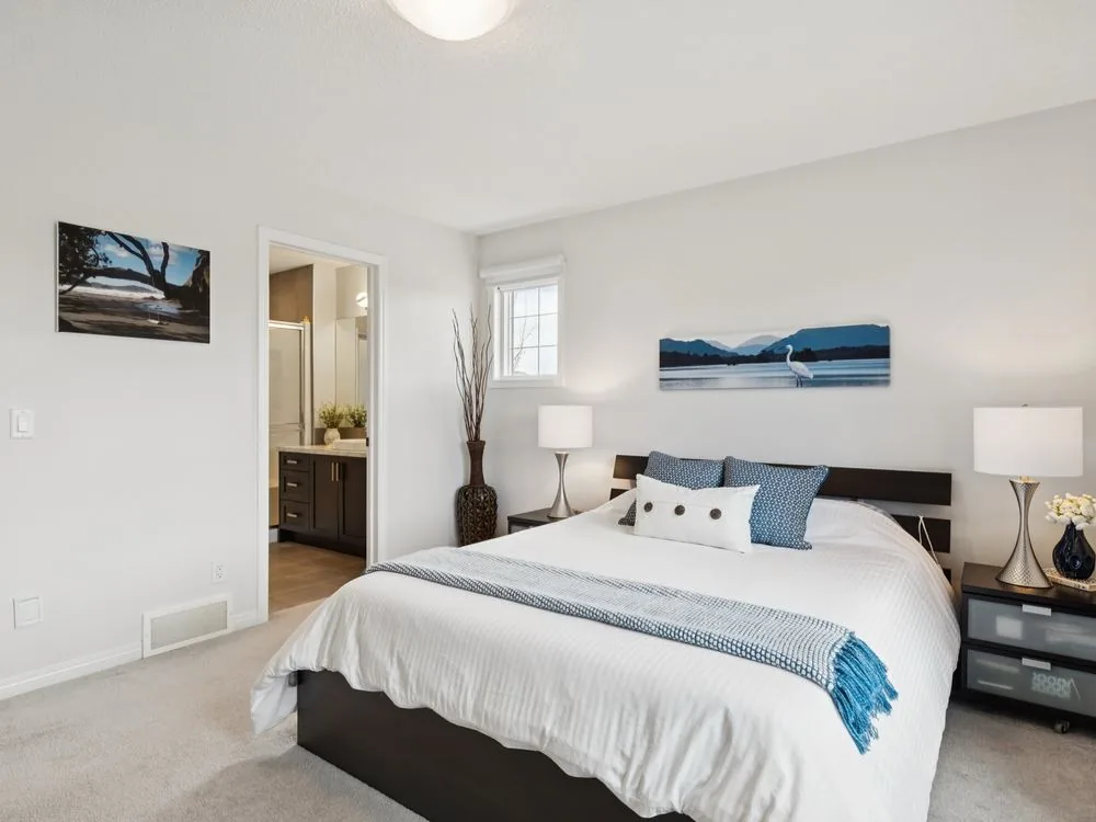The same bedroom after staging and professional photography: layered bedding, matching lamps, wall art and bright, even light